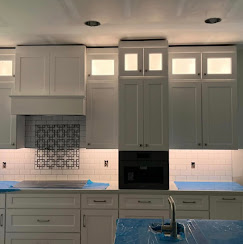 Kitchen cabinetry with finished backsplash and lighting